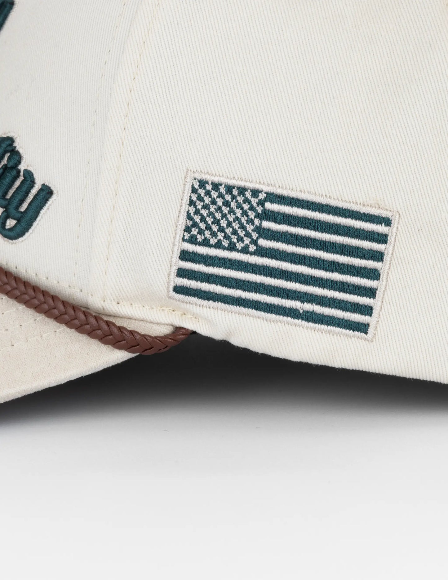 Off-white baseball cap with dark green embroidered american flag patch and partial city branding long live country hat