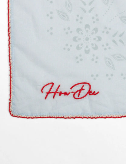 White handkerchief with red embroidered border how-dee logo and gray floral lace pattern in opry paisley traveler bandana blue