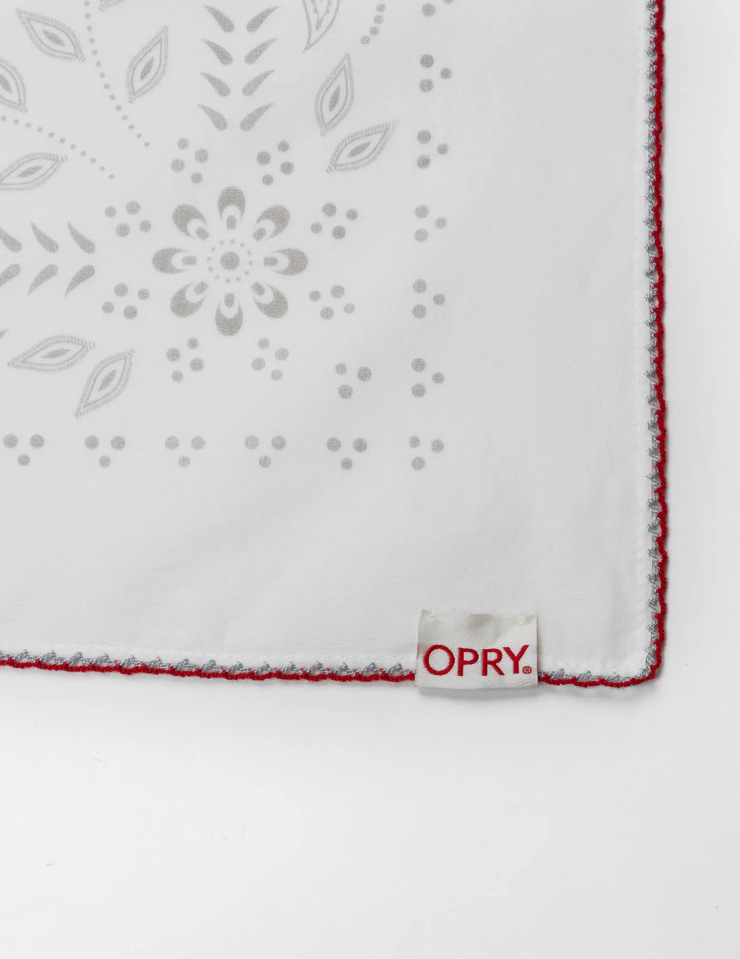 White embroidered handkerchief with gray floral patterns and red stitched edge in the opry paisley traveler bandana cream