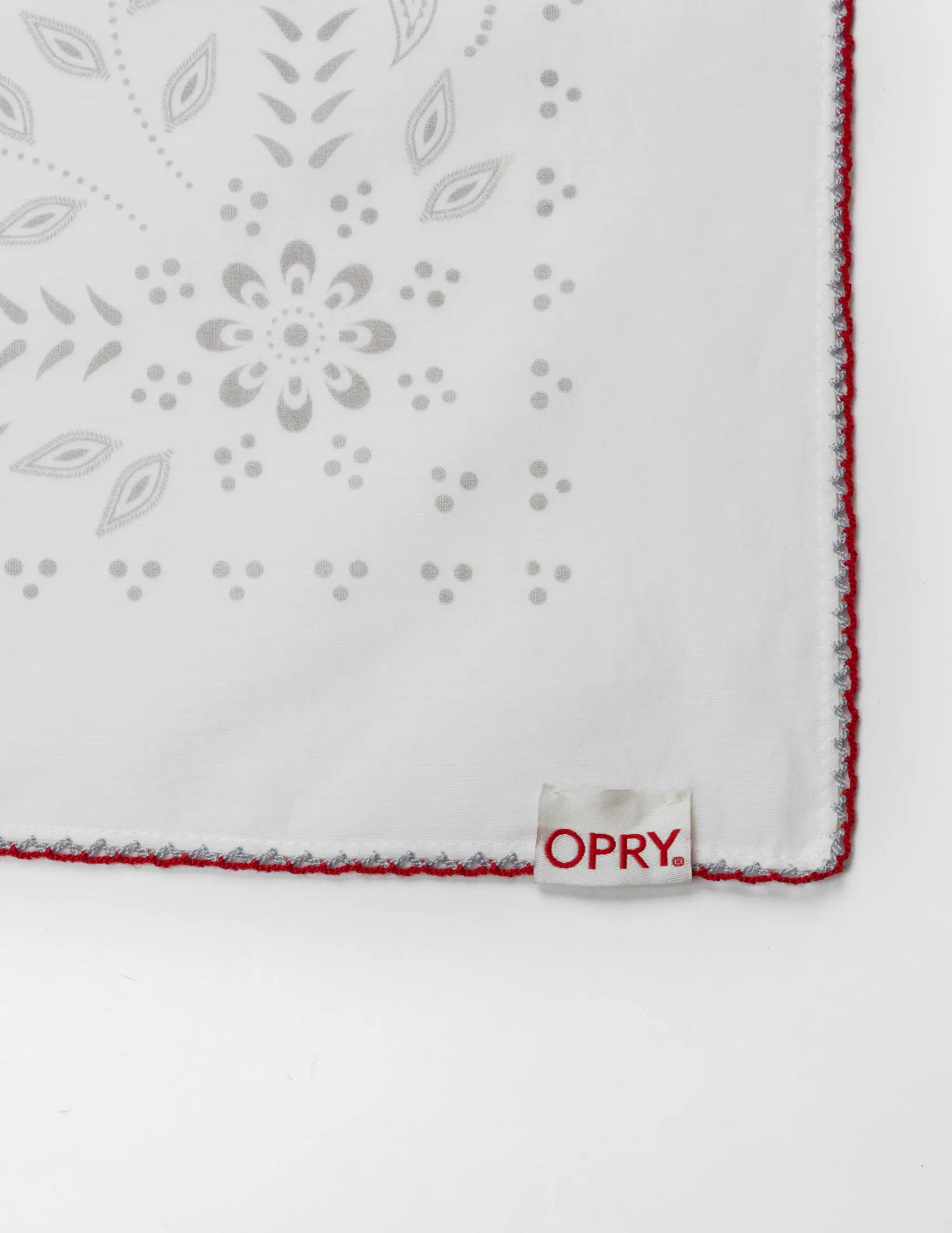 White embroidered handkerchief with gray floral patterns and red stitched edge in the opry paisley traveler bandana cream