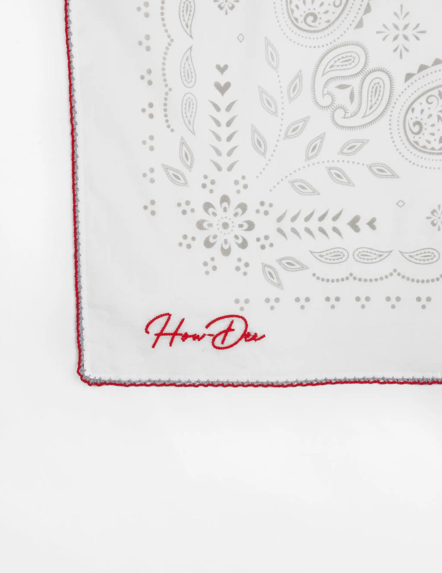 Opry paisley traveler bandana in cream with white fabric, gray paisley and floral embroidery, red edge stitching, and how den logo