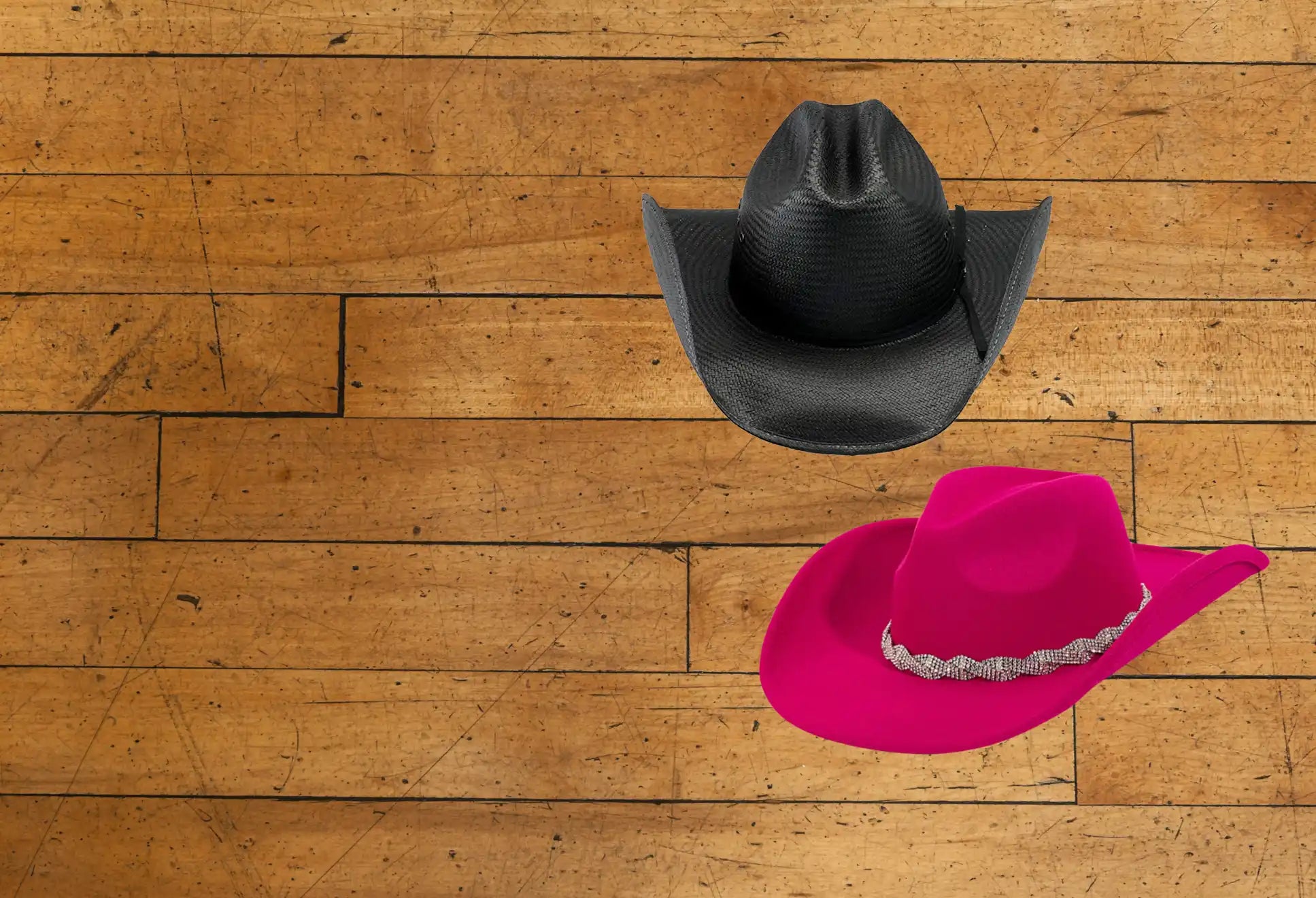 Two cowboy hats, one black and one fuchsia with a decorative band.
