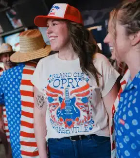 A cream-colored short-sleeved t-shirt with a colorful graphic of a guitar and wings.